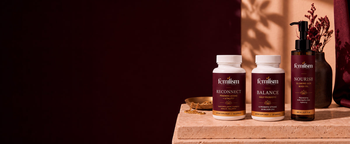 Femilism Reconnect, Balance and Nourish displayed together on a travertine stone slab against a deep burgundy background
